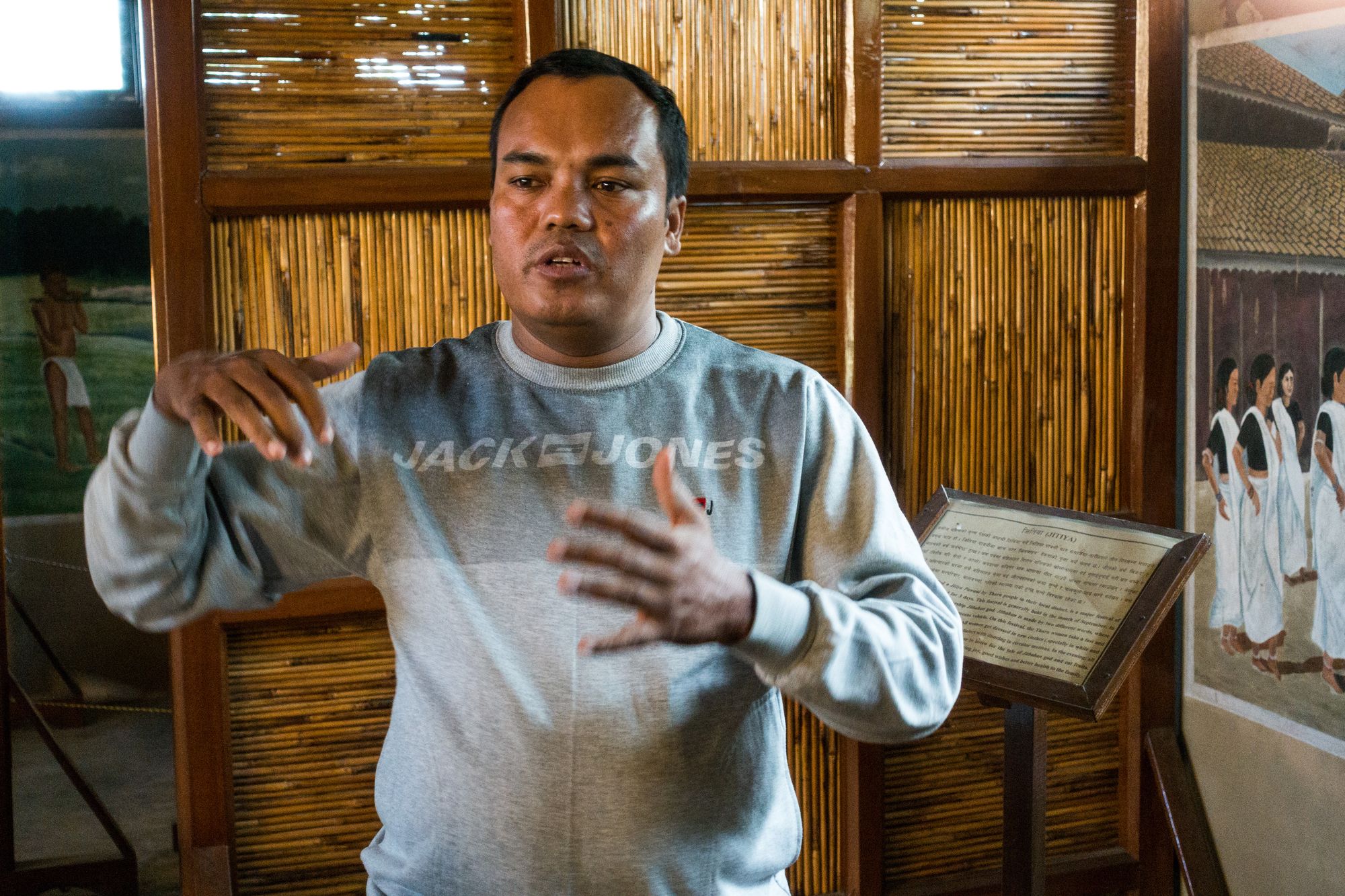 Birendra Mahato, chairperson of the Tharu Cultural Museum and Research Center, stands giving a speech whilst gesturing his hands.