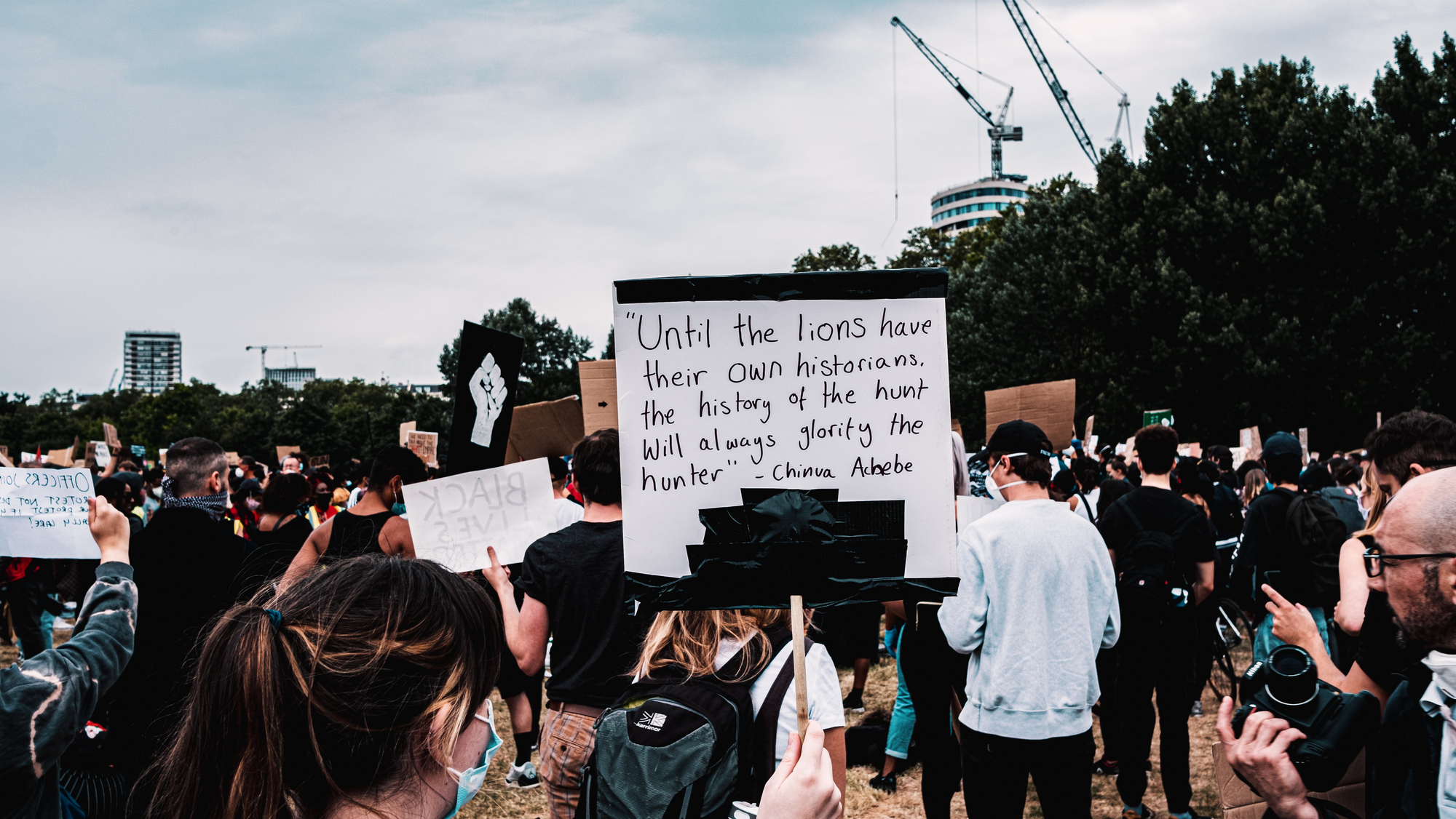 At a Black Lives Matter protest, somebody holds up a placard that reads, 'Until the lions have their own historians, the history of the hunt will always glorify the hunter. - China Achebe'