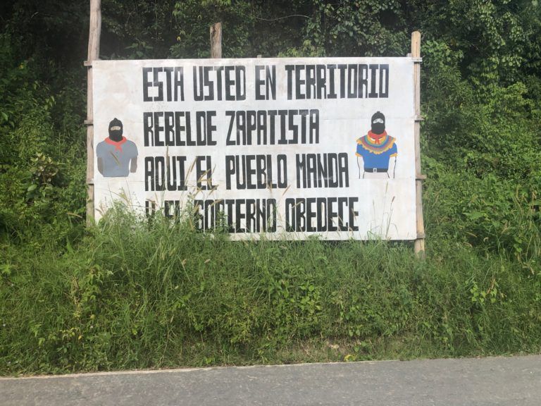 A sign by the side of a road, it reads: "Esta usted en territorio rebelde Zapatista aqui el pueblo manda y el gorierno obedece."